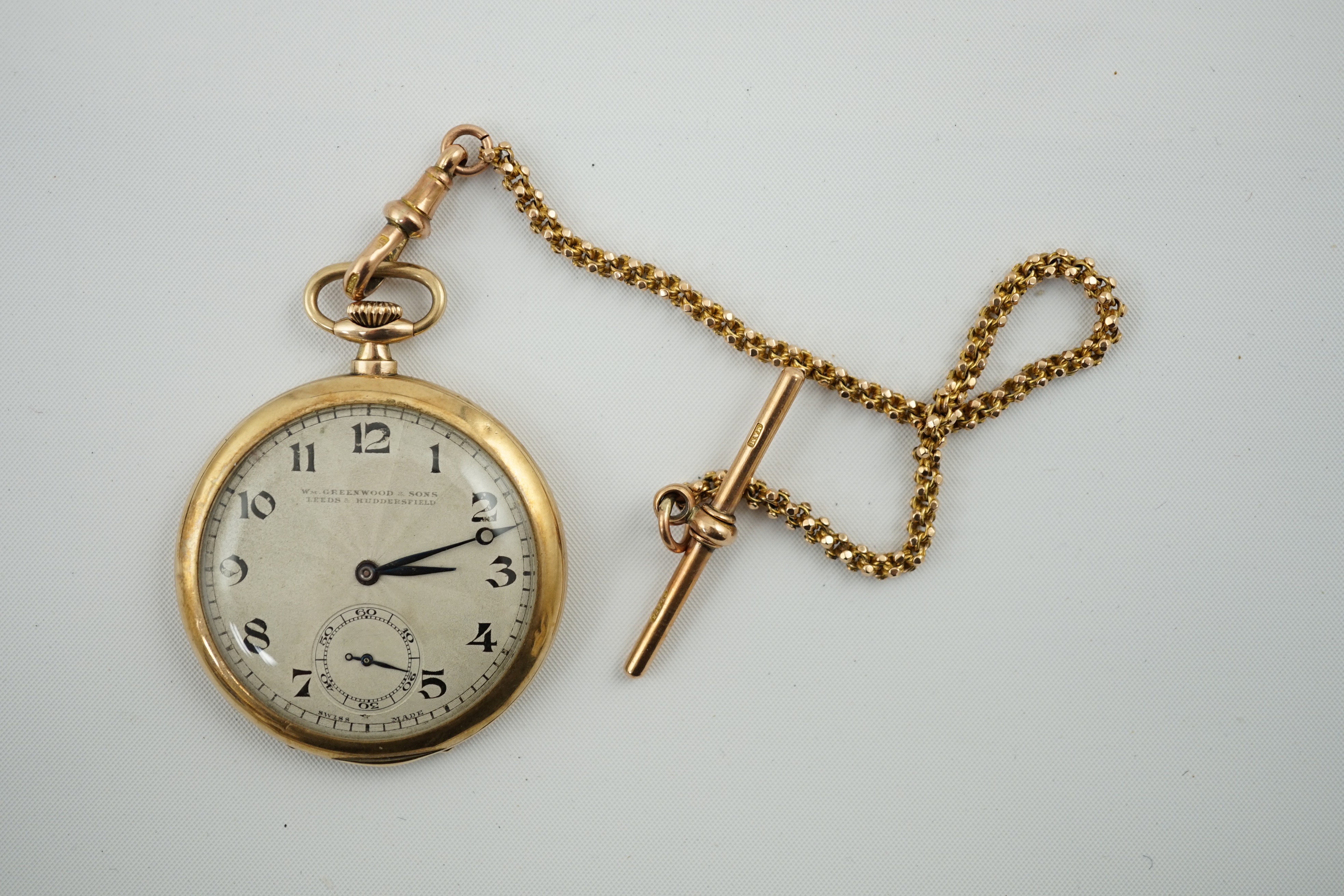 A George V 9ct gold open face dress pocket watch, retailed by William Greenwood & Sons, together with a 9ct gold albert